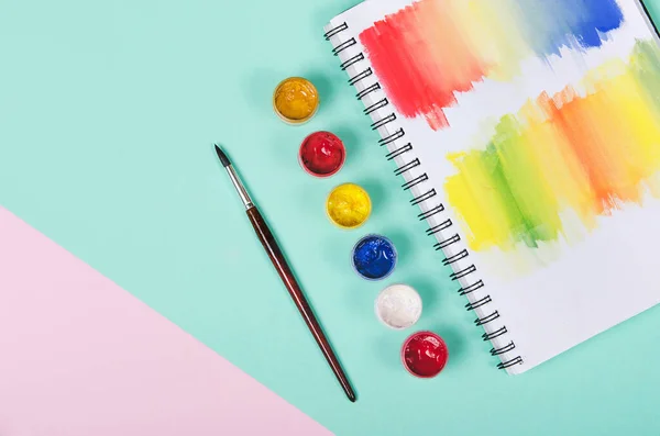 Boyalı şişeler ve beyaz üzerine renkli not defteriyle fırçalar.