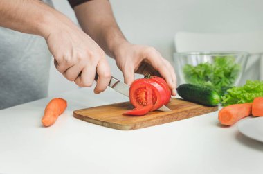 Erkek eller salata hazırlıyor. Domates doğrama. Sağlıklı yemek kavramı