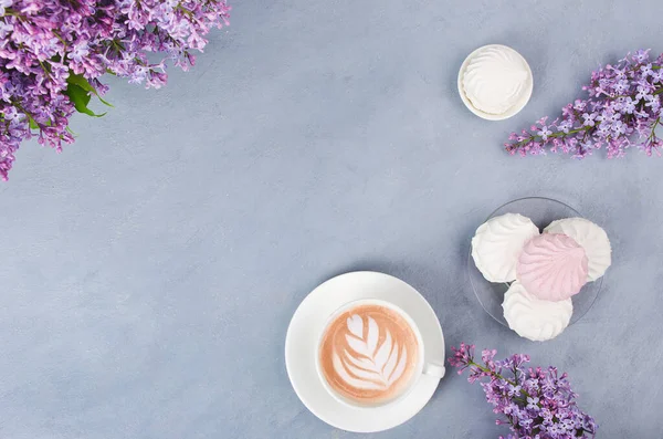 Lilac, coffee with latte art and marshmallow on gray wooden table. Romantic morning. Flat lay — Stock Photo, Image