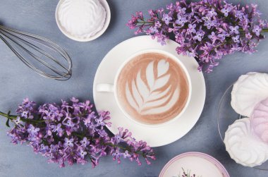 Leylak, latte sanatıyla kahve ve gri ahşap masada lokum. Romantik bir sabah. Düz yatıyordu