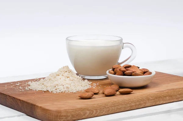 Almond milk in cup with almond flour and nuts on white background — Stock Photo, Image