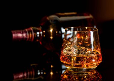 Cam ve bir şişe viski siyah arka plan üzerine buzlu viski