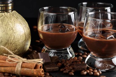 Çikolata, kahve, kremalı likörü kahve çekirdekleri, çikolata ve tarçın ile kokteyl. Siyah bir arka plan üzerinde. Noel alkollü içki