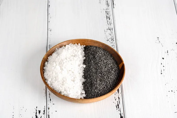 Dos tipos de sal. Sal marina blanca y sal negra del Himalaya en un tazón de madera sobre fondo blanco — Foto de Stock