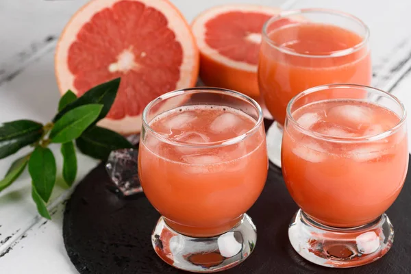 Zumo de pomelo y pomelos maduros sobre fondo de madera —  Fotos de Stock