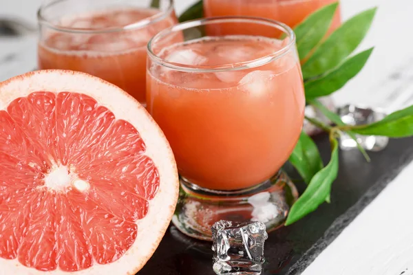 Грейпфрутовый сок и спелые грейпфруты на деревянном фоне — стоковое фото