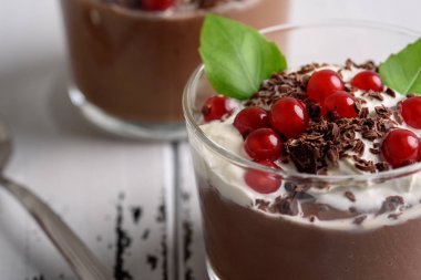 Frenk üzümü ve nane bir gözlük whiite ahşap arka plan üzerinde çikolata mousse.