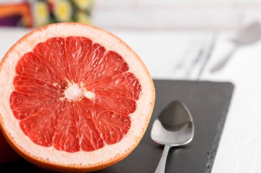 Beyaz ahşap masa üzerinde siyah taş zemin üzerine kaşıkla greyfurt