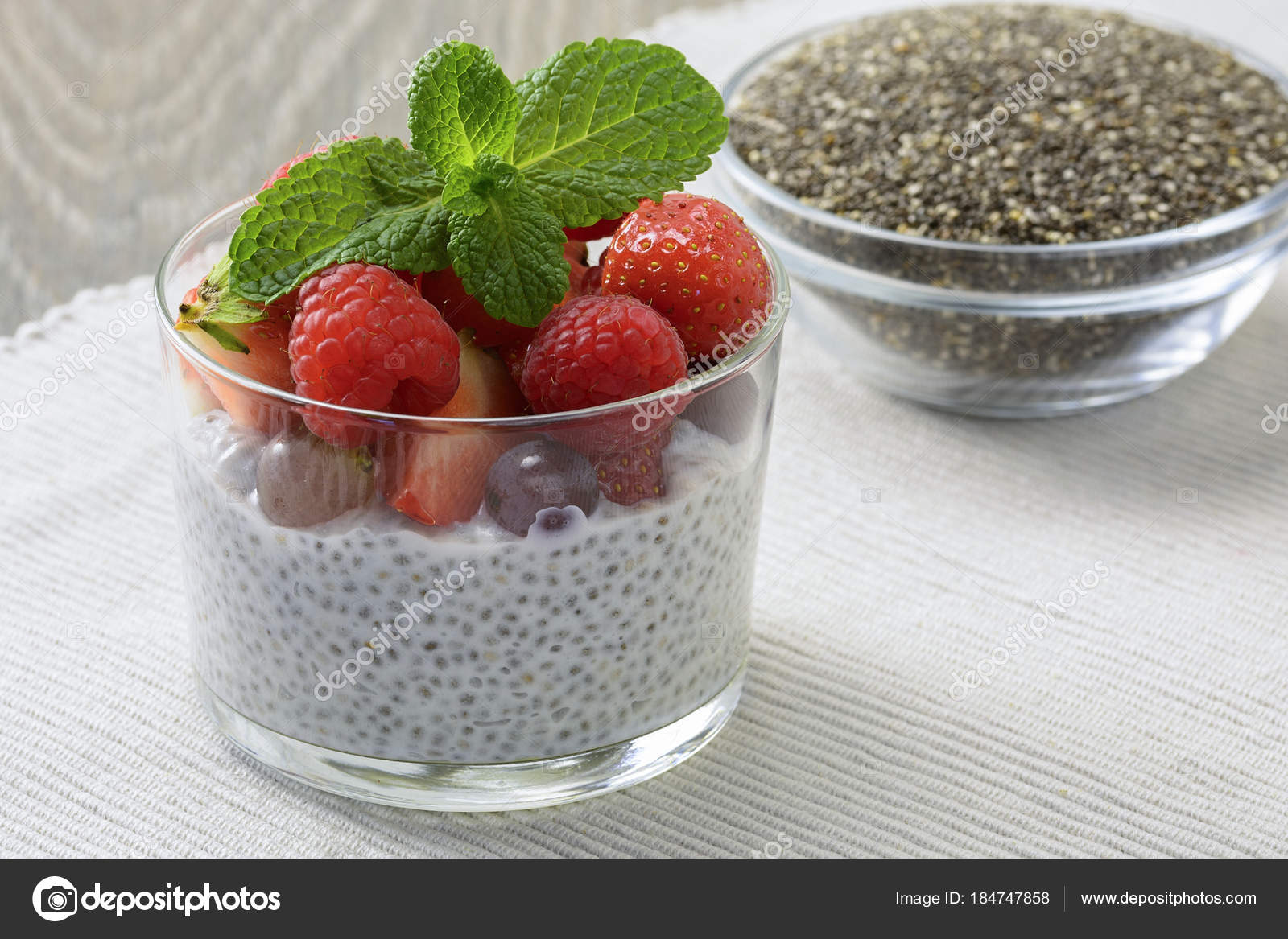 Healthy coconut milk chia pudding in a glass with fresh berries, leaves  mint and chia seeds in glass bowl Stock Photo by ©Bera_berc 184747858
