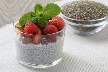 Bir bardak taze çilek ile sağlıklı Hindistan cevizi sütü chia puding yaprakları nane ve chia tohum cam kase