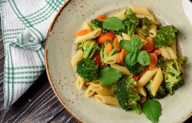 İtalyan ev yemekleri. Sebze makarna brokoli, domates, havuç, sarımsak ve fesleğen ile. Üstten Görünüm