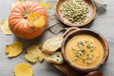 Sonbahar yaprakları ve kabak ile ahşap bir kase kabak çorbası