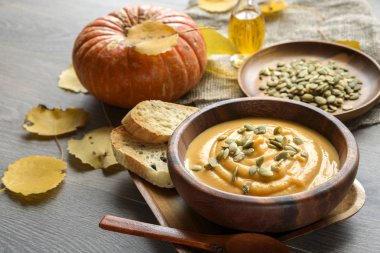 Sonbahar yaprakları ve kabak ile ahşap bir kase kabak çorbası
