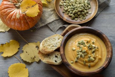 Sonbahar yaprakları ve kabak ile ahşap bir kase kabak çorbası