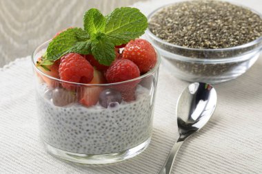 Bir bardak taze çilek ile sağlıklı Hindistan cevizi sütü chia puding yaprakları nane ve chia tohum cam kase