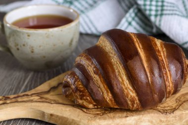 Taze kruvasanlar ve ahşap antika masa günü kahvaltıda çay bardağı