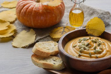 Sonbahar yaprakları ve kabak ile ahşap bir kase kabak çorbası