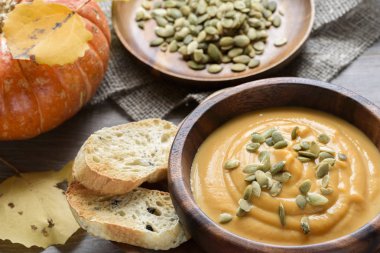 Sonbahar yaprakları ve kabak ile ahşap bir kase kabak çorbası