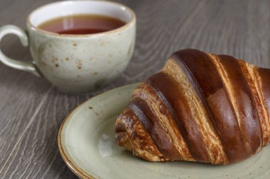 Taze kruvasanlar ve ahşap antika masa günü kahvaltıda çay bardağı