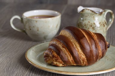 Taze kruvasanlar ve ahşap antika masa günü kahvaltıda çay bardağı