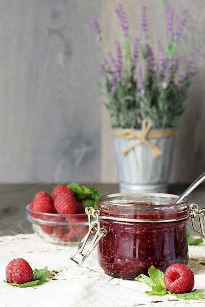 Mermelada de frambuesa en un frasco de vidrio con bayas de frambuesa frescas — Foto de Stock