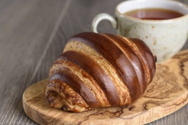 Taze kruvasanlar ve ahşap antika masa günü kahvaltıda çay bardağı
