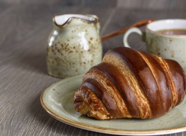 Taze kruvasanlar ve ahşap antika masa günü kahvaltıda çay bardağı