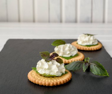 Bisküvi kraker meze ile krem peynir ve fesleğen tepesi