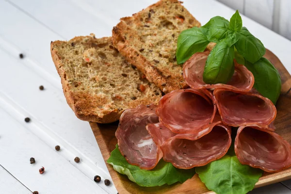 Salami smoked sausage slices basil leaves and peppercorns on whi — Stock Photo, Image