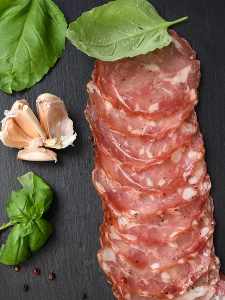 Salami, gerookte worst segmenten basilicum en peperkorrels op bla — Stockfoto