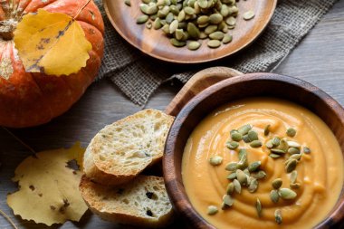 Sonbahar yaprakları ve kabak ile ahşap bir kase kabak çorbası