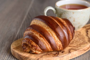 Taze kruvasanlar ve ahşap vintage sekmesinde kahvaltıda çay bardağı