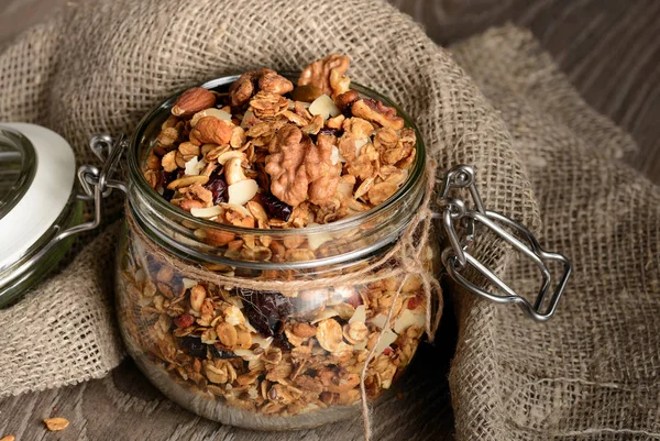 Homemade granola in open glass jar on rustic wooden background — Stock Photo, Image