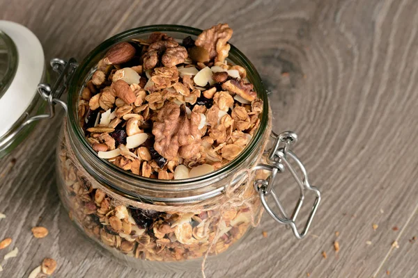 Homemade granola in open glass jar on rustic wooden background — Stock Photo, Image