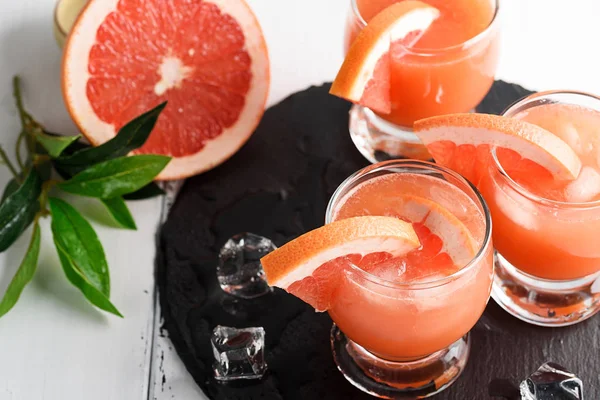 Грейпфрутовый сок и спелые грейпфруты на деревянном фоне — стоковое фото