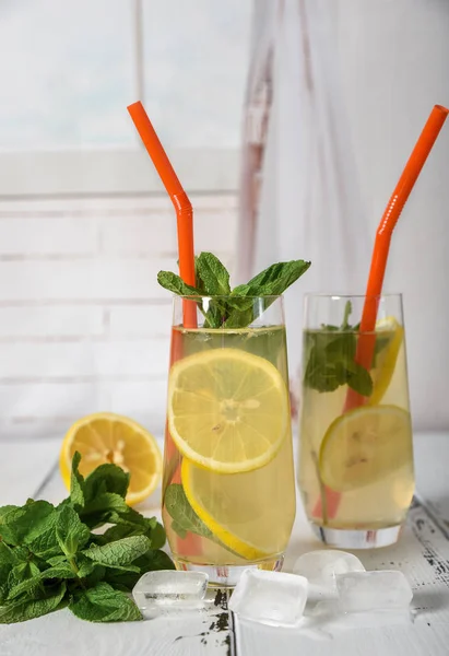Refrescante bebida fría de verano con limón y menta en respaldo de madera —  Fotos de Stock