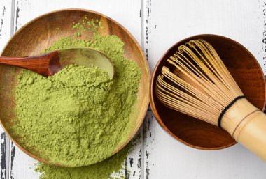 Yeşil çay matcha tozu çırpma teli ve bir yeşil bir ahşap kase 