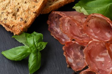 Salam sosis dilimleri fesleğen yaprakları ve karabiber bla üzerinde füme