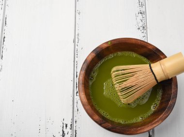 Yeşil çay matcha tozu çırpma teli ve bir yeşil bir ahşap kase 