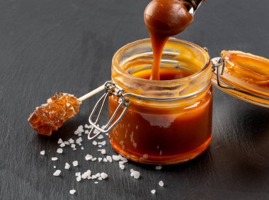 Kaşık kavanoz tablo üzerinde lezzetli karamel sos ile