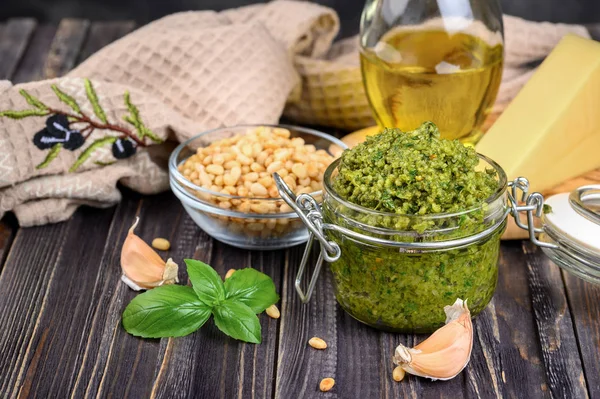 Salsa de pesto en un frasco con piñones, parmesano y ajo sobre da — Foto de Stock