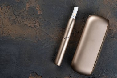 19 Ocak 2020, Monchegorsk, Rusya. Siyah arka planda altın renkli iqos elektronik sigara, Marlboro ve Philippe Morris Iqos, analog ve elektronik arasında melez sigara olarak tanımlanır.
