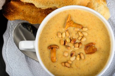 Mantar, çam fıstıklı chanterelle kremalı çorba ve koyu arkaplanda kızarmış ekmek. Üst görünüm, alanı kopyala