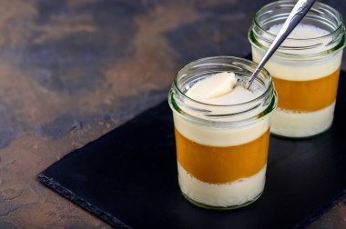 Tatlı. Mangolu hindistan cevizi sütlü panna cotta, İtalyan tatlısı, koyu siyah arka planda ev yapımı. Kopyalama alanı