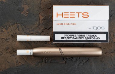 19 Ocak 2020, Monchegorsk, Rusya. Siyah arka planda altın renkli iqos elektronik sigara, Marlboro ve Philippe Morris Iqos, analog ve elektronik arasında melez sigara olarak tanımlanır.