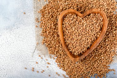 Kalp şeklinde karabuğdaylar arka planda kesme tahtası. Üst görünüm.