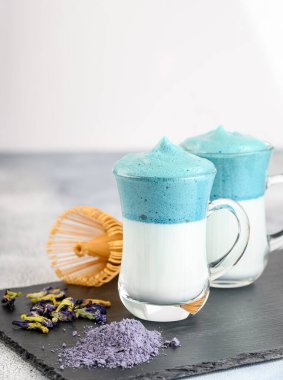 Dalgona Matcha Blue Latte, açık arkaplanda cam kırbaçlanmış kremalı kibrit.. 
