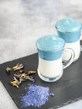 Dalgona Matcha Blue Latte, açık arkaplanda cam kırbaçlanmış kremalı kibrit.. 