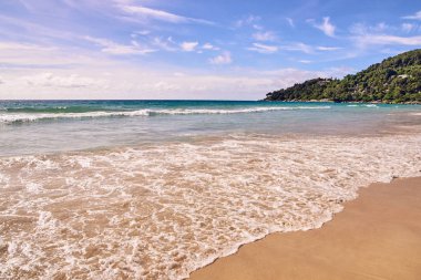 Mavi gökyüzü. Dalgalar deniz. Yeşil ağaçlar. Parlak kum