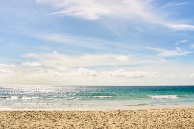 Sıcak mavi deniz. Beyaz bulutlar. Hafif kum